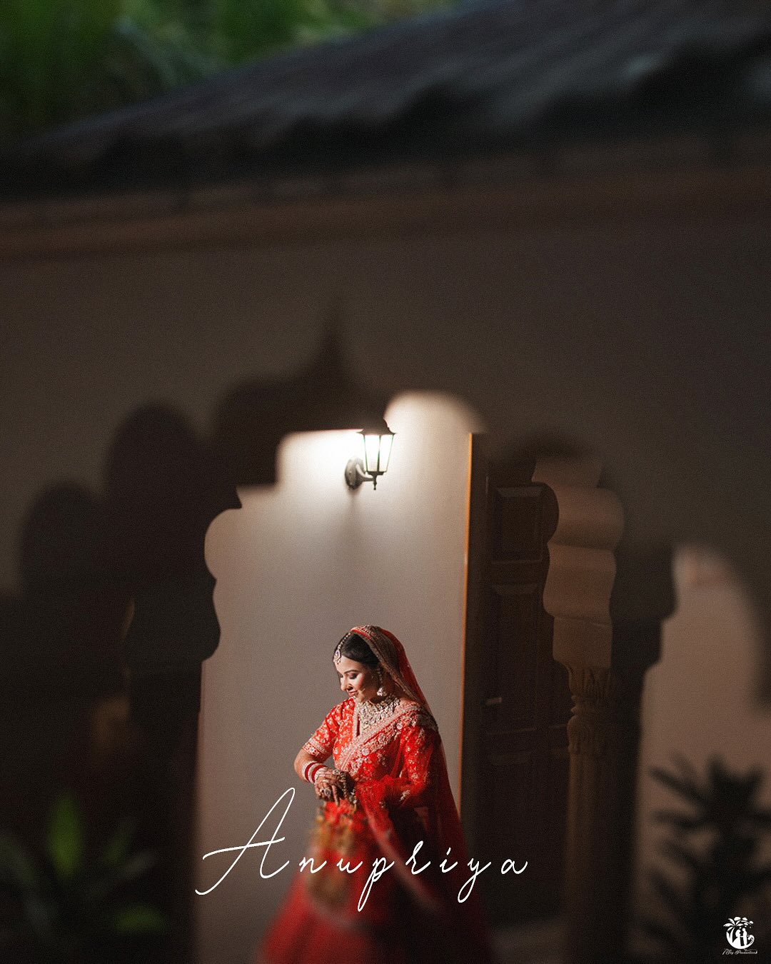 Bride in red lehenga framed by a scalloped Mughal-style arch at dusk - heritage pre wedding shoot idea by 7thSky Productions