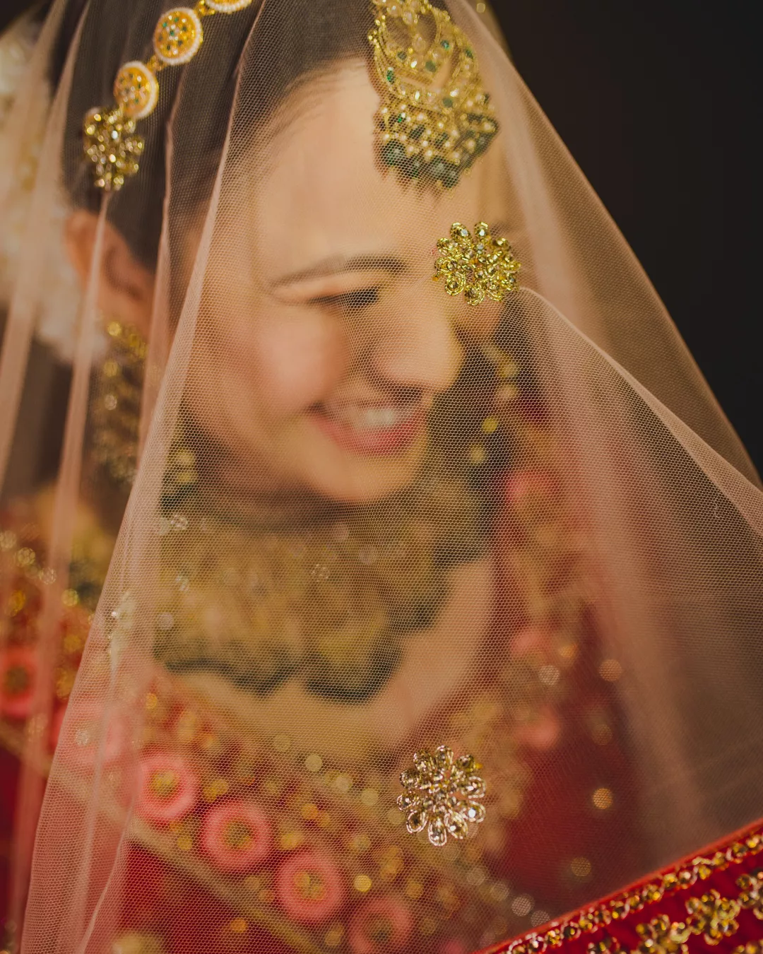 Bride smiling under her veil at a Gurgaon wedding, portfolio photo by Shaadi Photographers