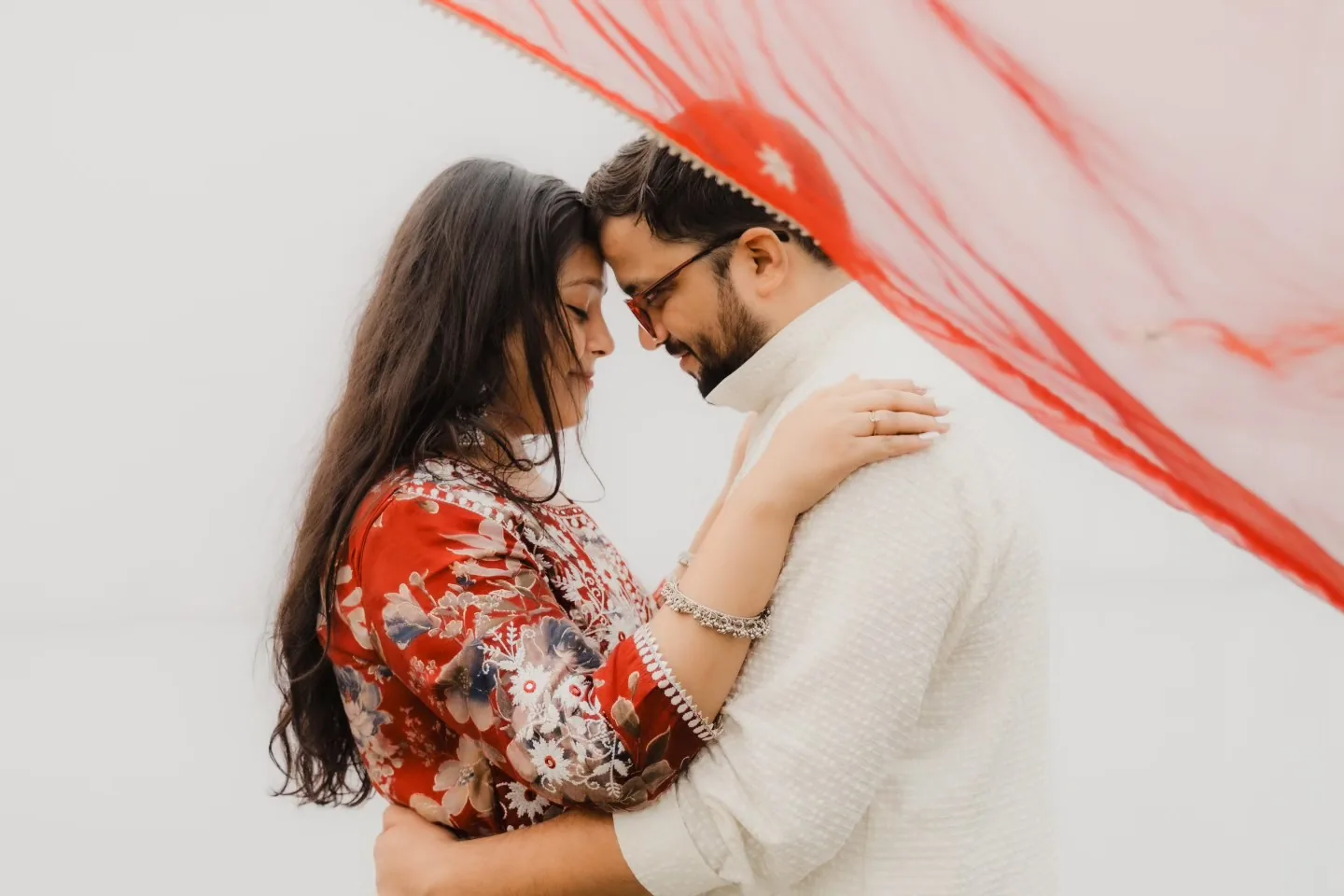 Pre wedding shoot in Gurgaon - couple embracing with a flowing red dupatta, portfolio photo by The Knotty Tellers